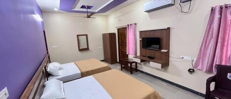 A hotel room with two beds, a ceiling fan, an air conditioning unit, a TV, and a desk.