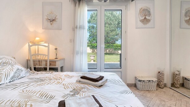 Een slaapkamer met een bed, een bureau, een stoel en uitzicht op de omgeving via een deur.