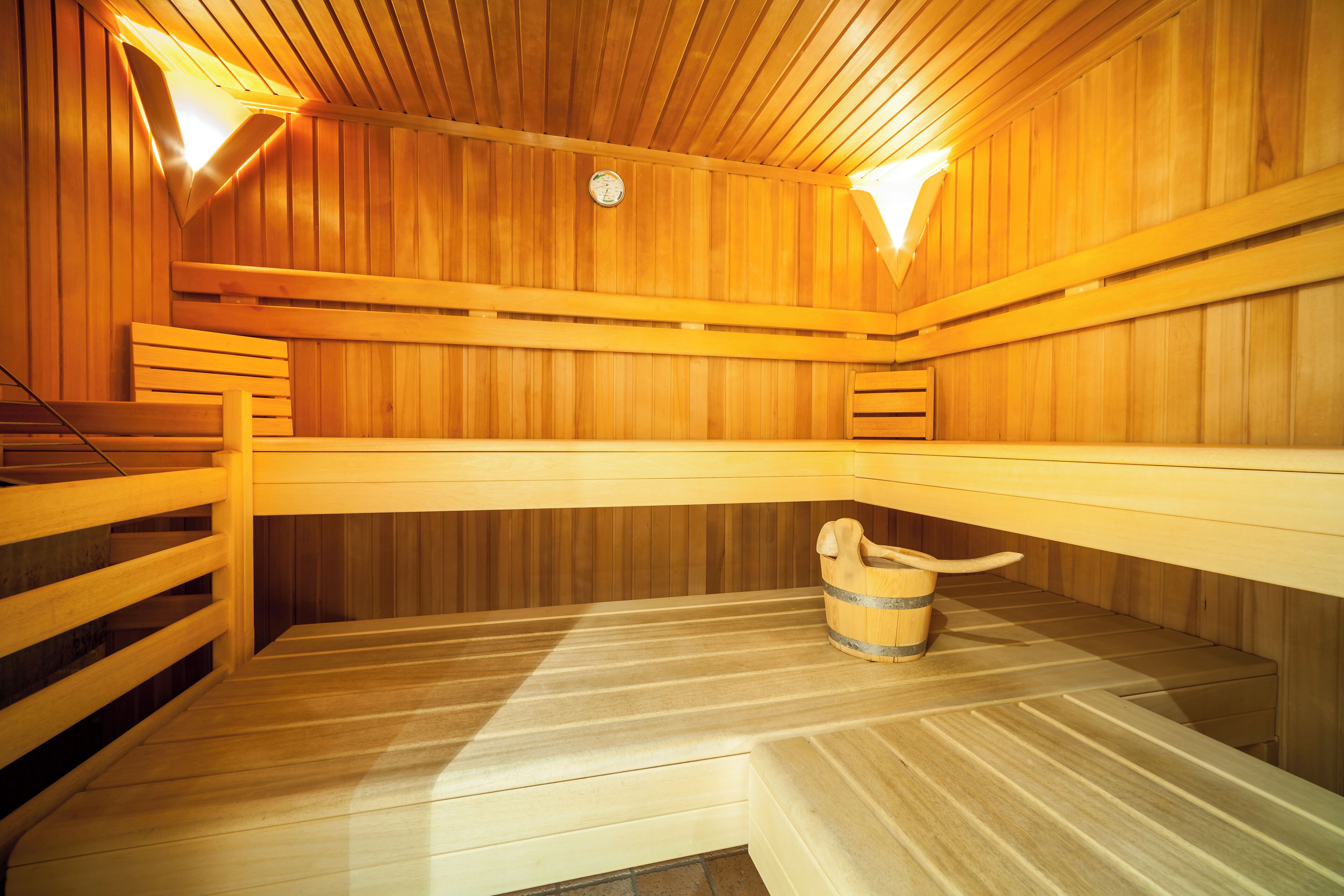 A sauna with wooden benches and a wooden bucket.