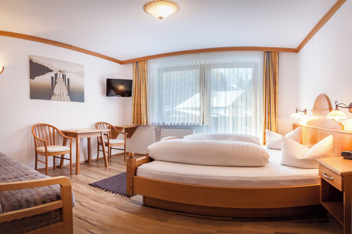 A modern hotel room with a round bed, a desk, a chair, and a television.