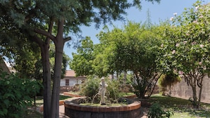 Un giardino con una statua, alberi e un vialetto in mattoni.
