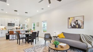 Una sala moderna con un sofá gris, una mesa de centro y un comedor con sillas y una mesa.