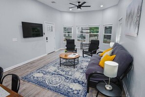 Un salon moderne avec un canapé, des fauteuils, une table basse et un téléviseur.