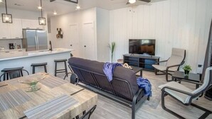 Een moderne keuken met witte kasten, een koelkast, en een eethoek met een tafel en stoelen.