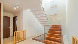 Un intérieur moderne avec un escalier en bois, une rampe en verre et une porte en bois.