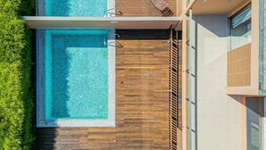 Un bâtiment moderne doté d’une piscine sur le toit, d’une terrasse en bois et de grandes fenêtres en verre.