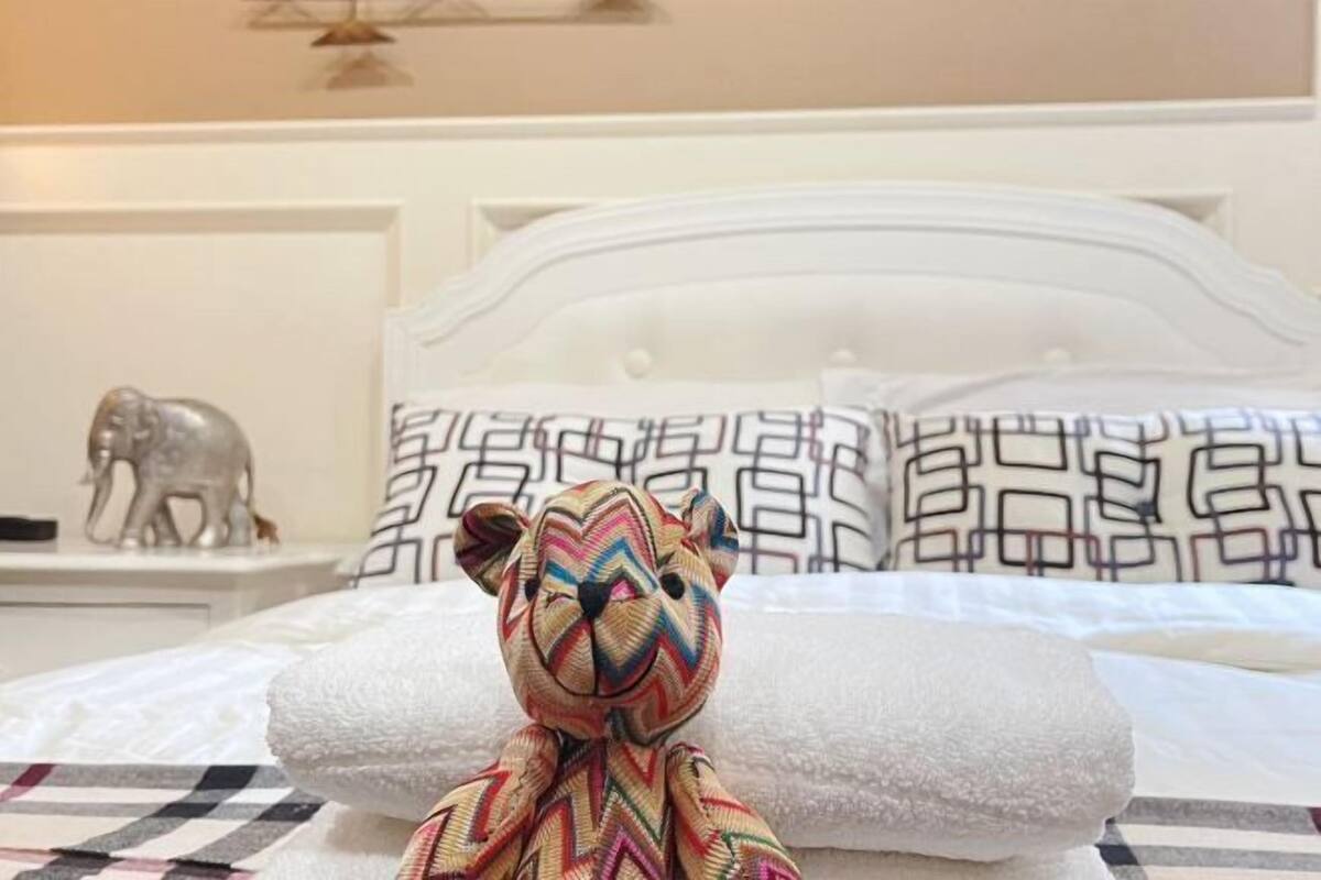 A bed with a white headboard, a patterned pillow, and a decorative elephant figurine on a nightstand.