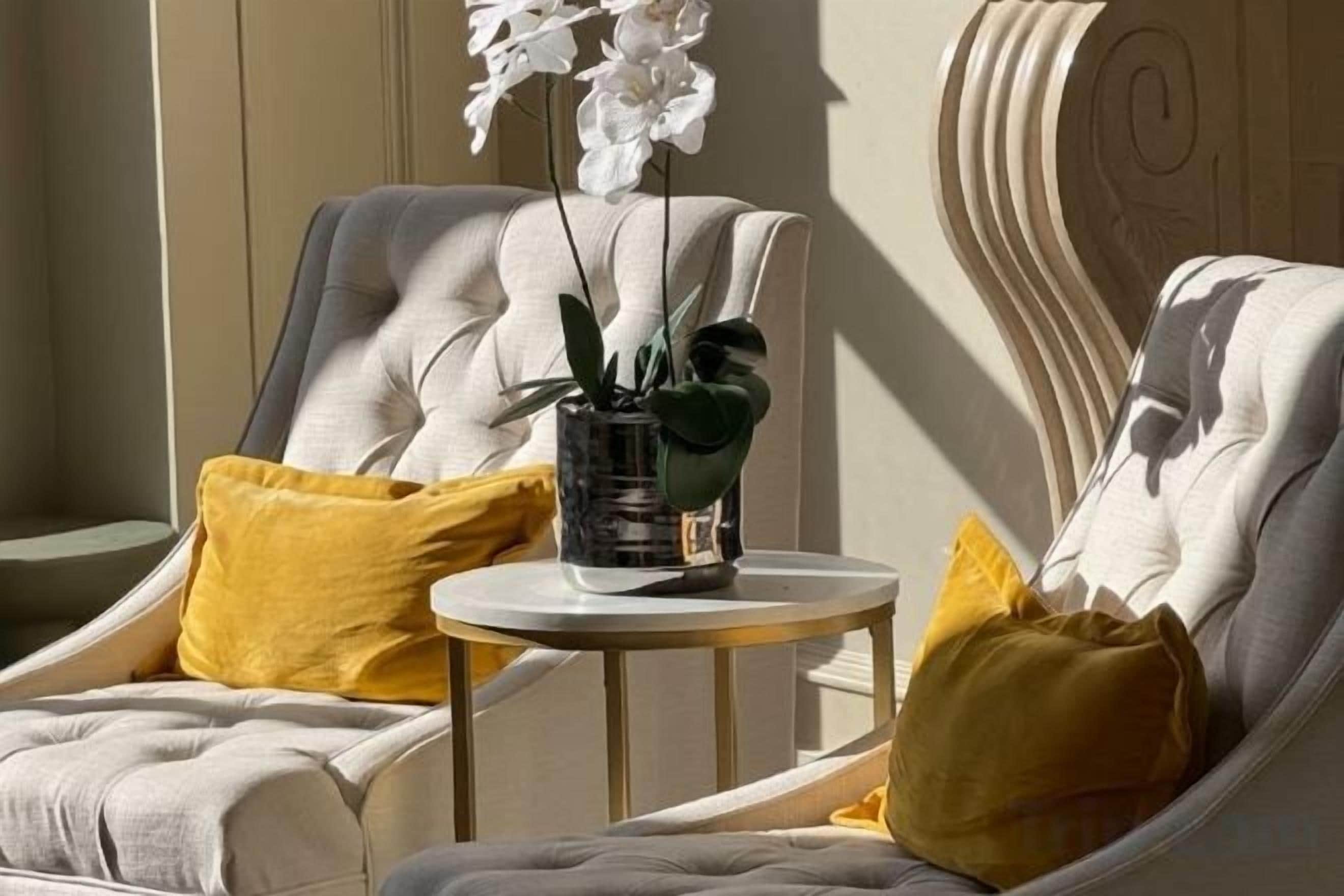 Un coin salon avec deux chaises, une petite table ronde et une plante en pot.