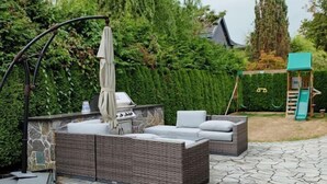 A patio with wicker furniture, a grill, and a play area in the background. - Vancouver Love Home Luxury Inn (Richmond)