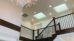 A staircase with a black railing and a chandelier. - Vancouver Love Home Luxury Inn (Richmond)