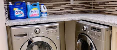 Un área de lavandería con dos lavadoras y botellas de detergente.