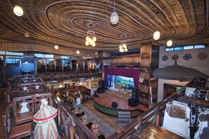 A spacious venue with a stage, wooden furniture, and a high ceiling with a circular design. - Yod Abyssinia International Hotel (Addis Ababa)