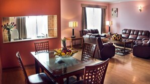 A living room with a glass-top dining table, leather sofas, and a large window with curtains. - Yod Abyssinia International Hotel  (Addis Ababa)
