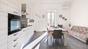 A modern kitchen with a dining area, a sofa, and a view through a door. - Apartment 'Casa Vacanze Lu Rizzaru' with Private Terrace, Balcony & Air Conditioning (Nardò)