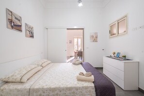 Een slaapkamer met een bed, een dressoir en twee schilderijen aan de muur.