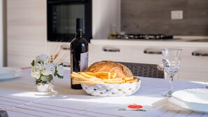A dining table with a bottle of wine, a basket of bread and fries, a glass of water, and a vase of flowers. - Apartment 'Casa Vacanze Lu Rizzaru' with Private Terrace, Balcony & Air Conditioning (Nardò)