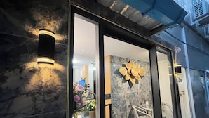 L’entrée d’un hôtel, avec une façade en marbre, une porte en verre et un mur décoré de fleurs.
