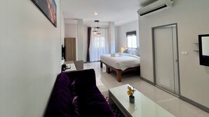 Une chambre d’hôtel moderne équipée d’un lit, d’un canapé, d’une table basse agrémentée de fleurs, d’un téléviseur et d’un appareil de climatisation.