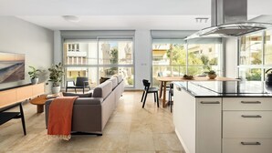 A modern kitchen with large windows, a dining area, and a living space with a sofa and coffee table. - Gordon Beach Bright Stay by Sea N' Rent (Tel Aviv)