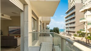 A balcony with a view of the sea, a sofa, and a chair. - Gordon Beach Bright Stay by Sea N' Rent (Tel Aviv)
