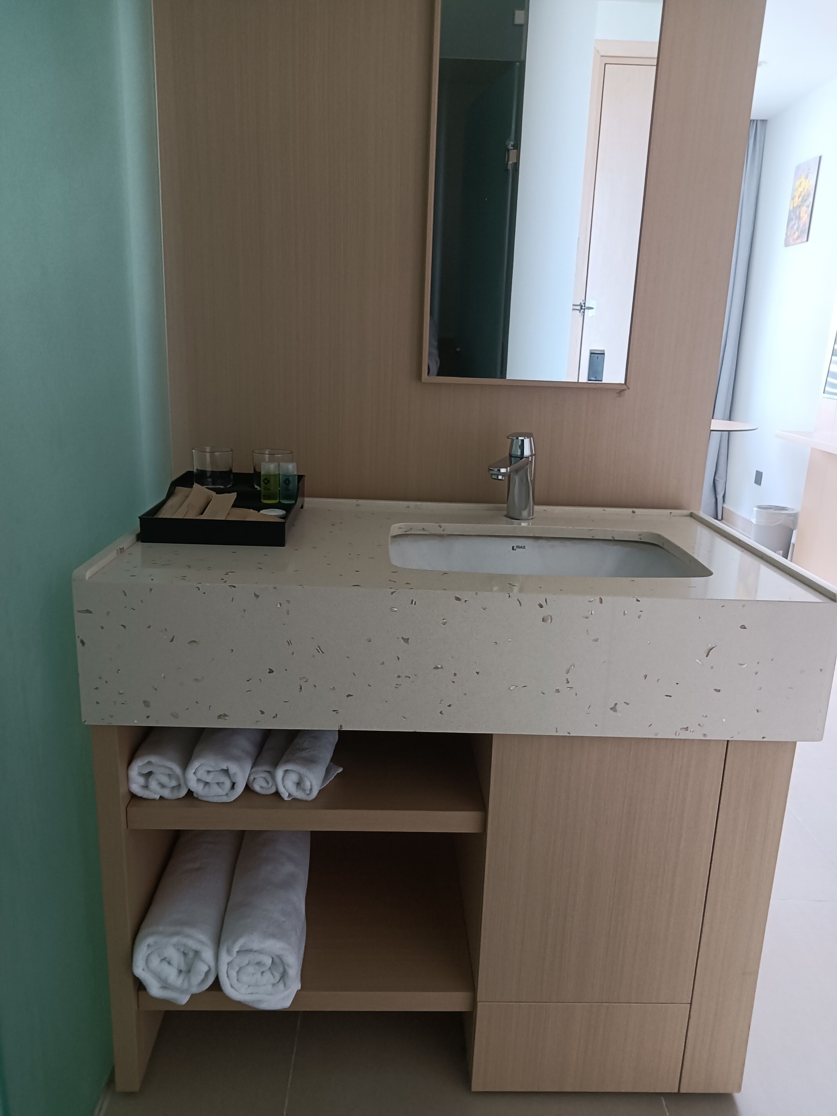 A bathroom with a sink, mirror, and towel storage.
