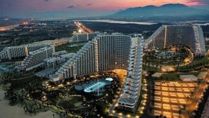 Een groot hotelcomplex met meerdere hoge gebouwen, een centrale binnenplaats met zwembaden en een omringend aangelegd gebied.