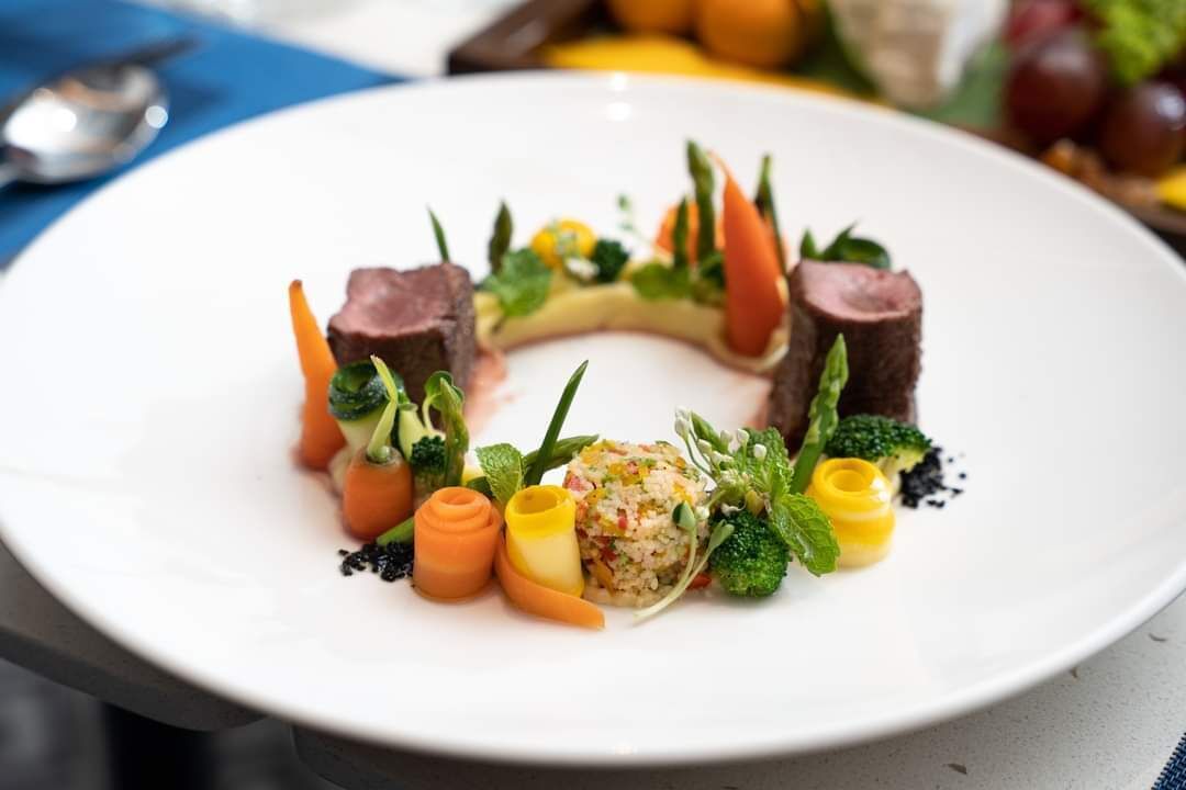 Een wit bord met diverse soorten eten, waaronder vlees, groenten en een kleine salade.