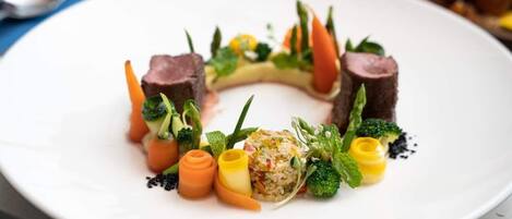 Een wit bord met diverse soorten eten, waaronder vlees, groenten en een kleine salade.