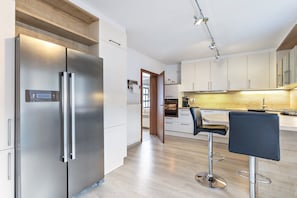 Eine moderne Küche mit Edelstahlgeräten, einer Holz Arbeitsplatte und einer Bar mit Hockern.