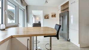 Une cuisine moderne avec un plan de travail en bois, des appareils en acier inoxydable et un tabouret de bar.