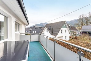Ein Balkon mit blauem Boden, weißen Wänden und einem Metallgeländer.