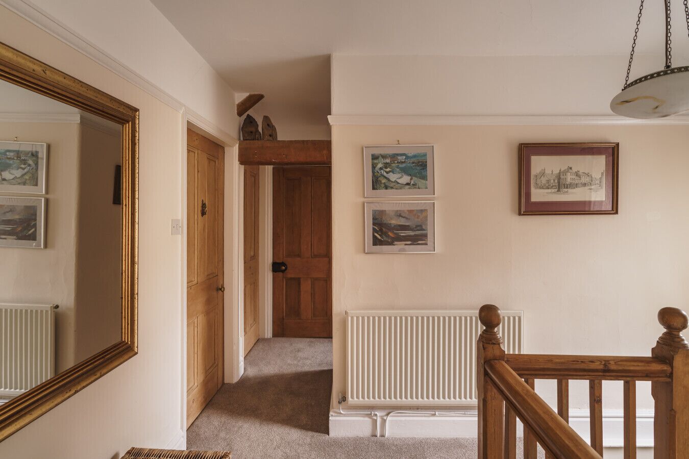 A hallway with a wooden door, a radiator, and framed pictures on the wall.
