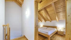 A bedroom with a wooden ceiling, a bed, a nightstand, and a wall-mounted light. - Ferienwohnung Lisa (Bad Mitterndorf)