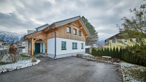 A wooden house with a sloped roof, a front porch, and a driveway leading to the entrance. - Ferienwohnung Lisa (Bad Mitterndorf)