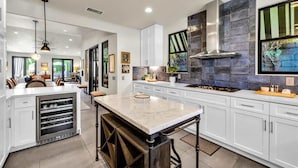 Una cocina moderna con armarios blancos, una isla de mármol y un amplio ventanal con vistas.