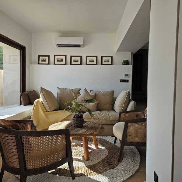 A modern living room with a sofa, two armchairs, a coffee table, and a large window.