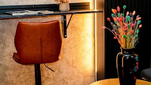 Een modern interieur met een lederen fauteuil, een vaas met kleurrijke bloemen en een plank vol tijdschriften.