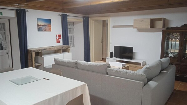 A living room with a sofa, a TV, a wooden cabinet, and a table.