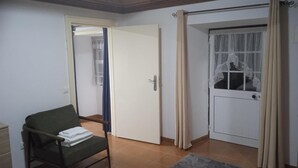 A room with a chair, a door, and a window with curtains. - Holiday Home 'Do Avô Almeida' with Mountain View, Balcony and Wi-Fi (Lajes das Flores)