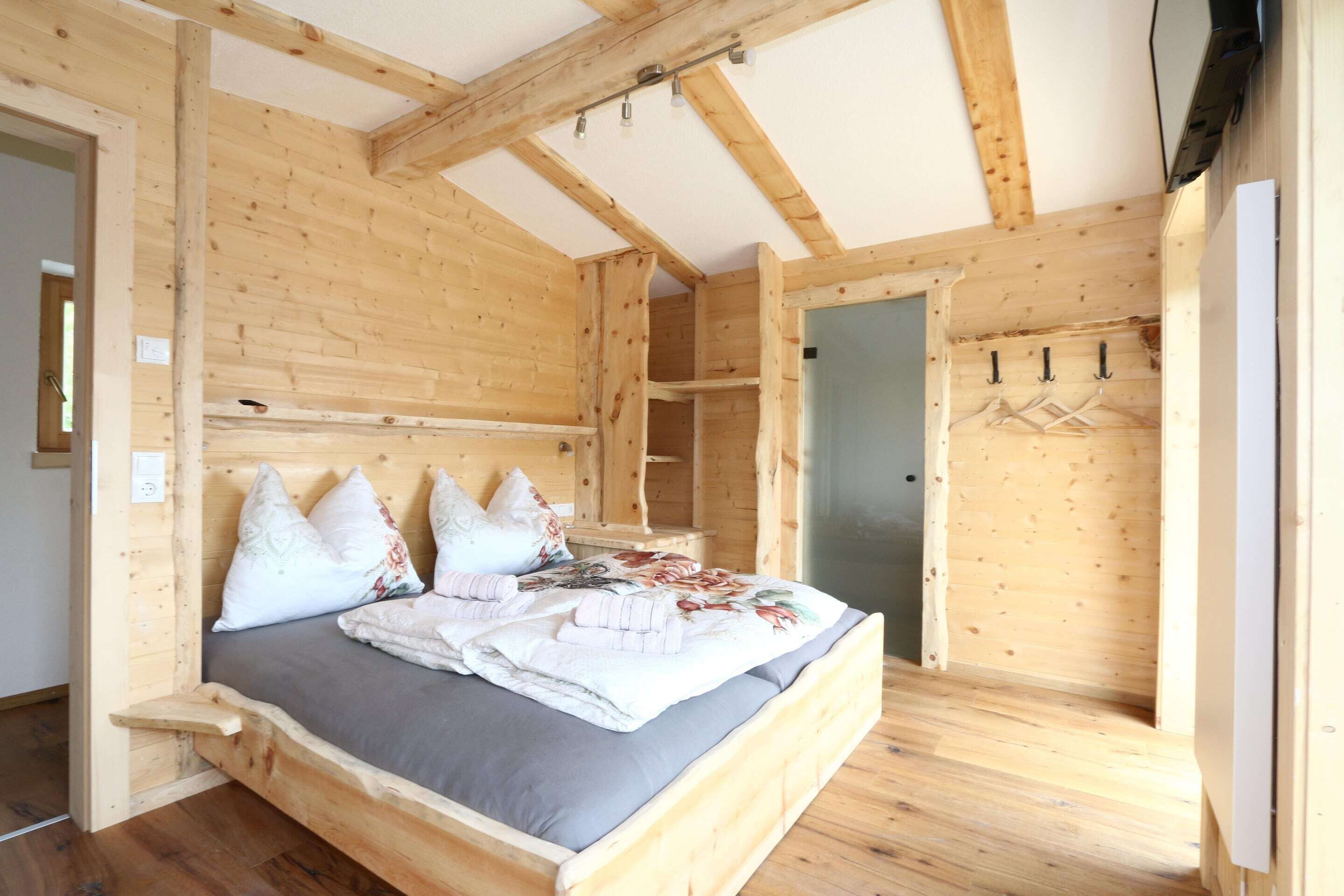 Um quarto de madeira com uma cama, um guarda-roupa e uma porta.
