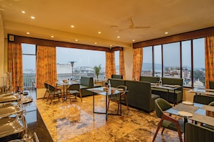 Un restaurante con vistas a la ciudad, que cuenta con un bar, zonas de estar y un suelo de mármol pulido.