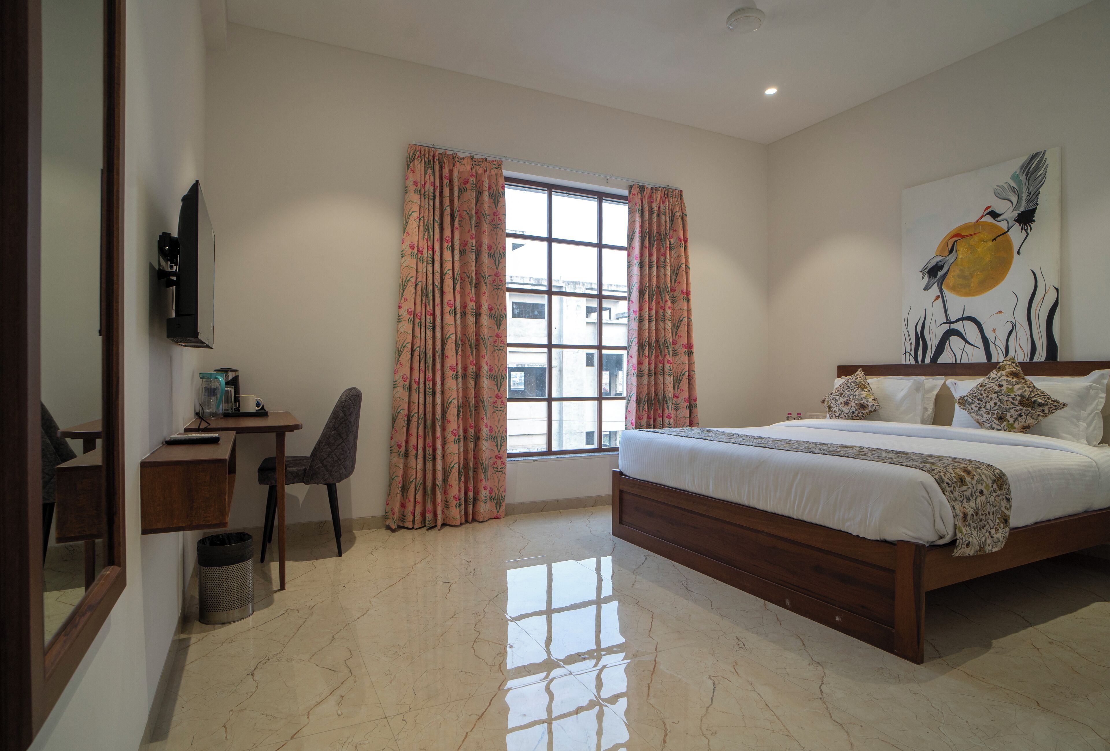 Un dormitorio con cama, escritorio, silla, televisión y ventana con cortinas.