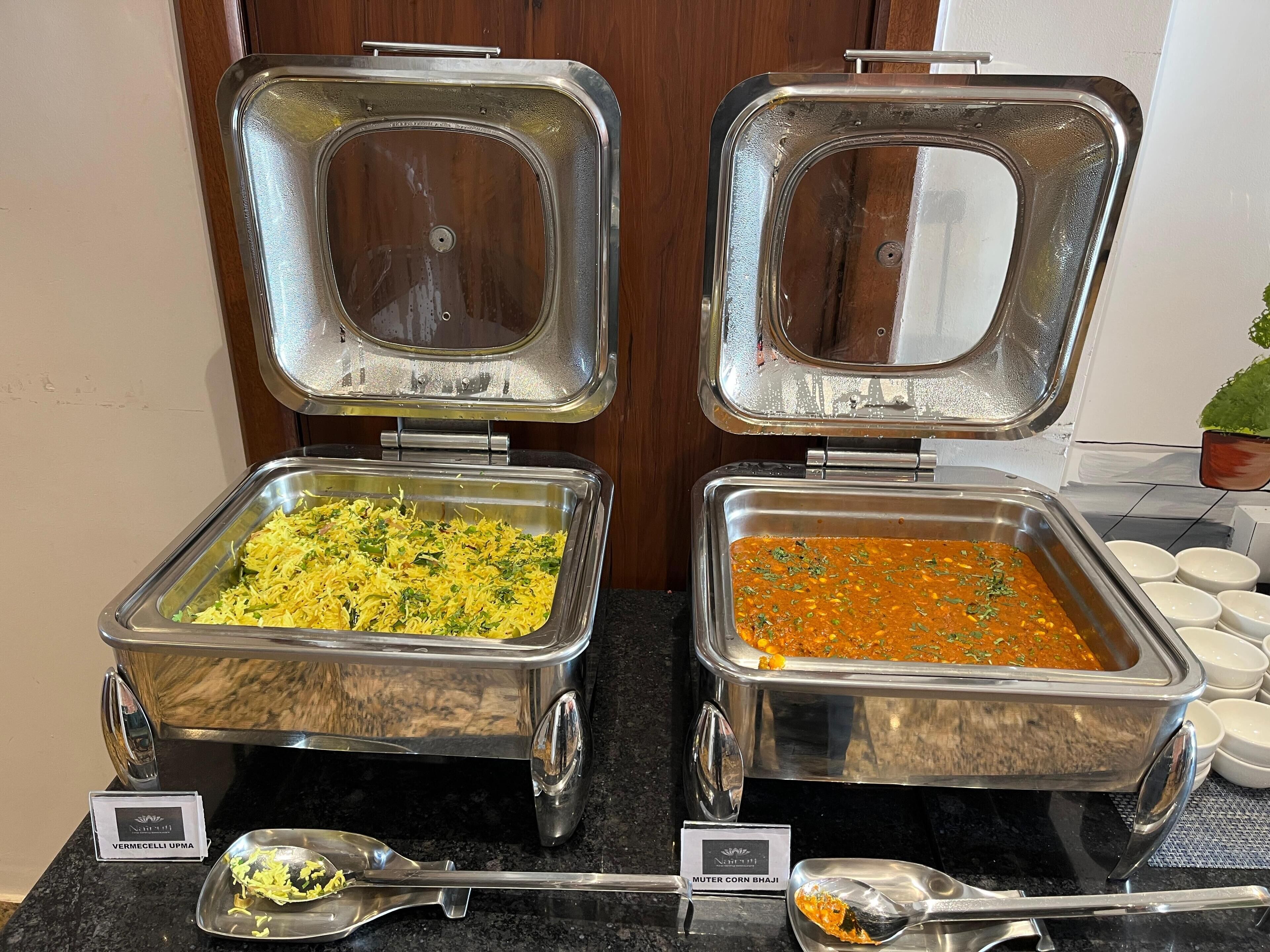 Dos estaciones de buffet con platos identificados: 'VERMECELLI UPMA' y 'MUTER CORN BHAJI'.
