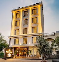 Un hotel de varios pisos con una entrada destacada, ventanas amplias y un letrero que indica un área de lounge.