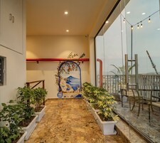 A corridor with a mural, potted plants, and a balcony with outdoor furniture.