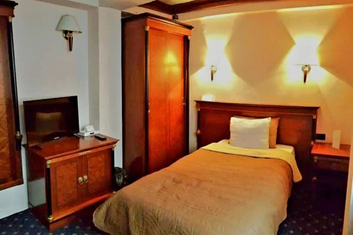 Una habitación de hotel con cama, escritorio con lámpara, armario y televisión.