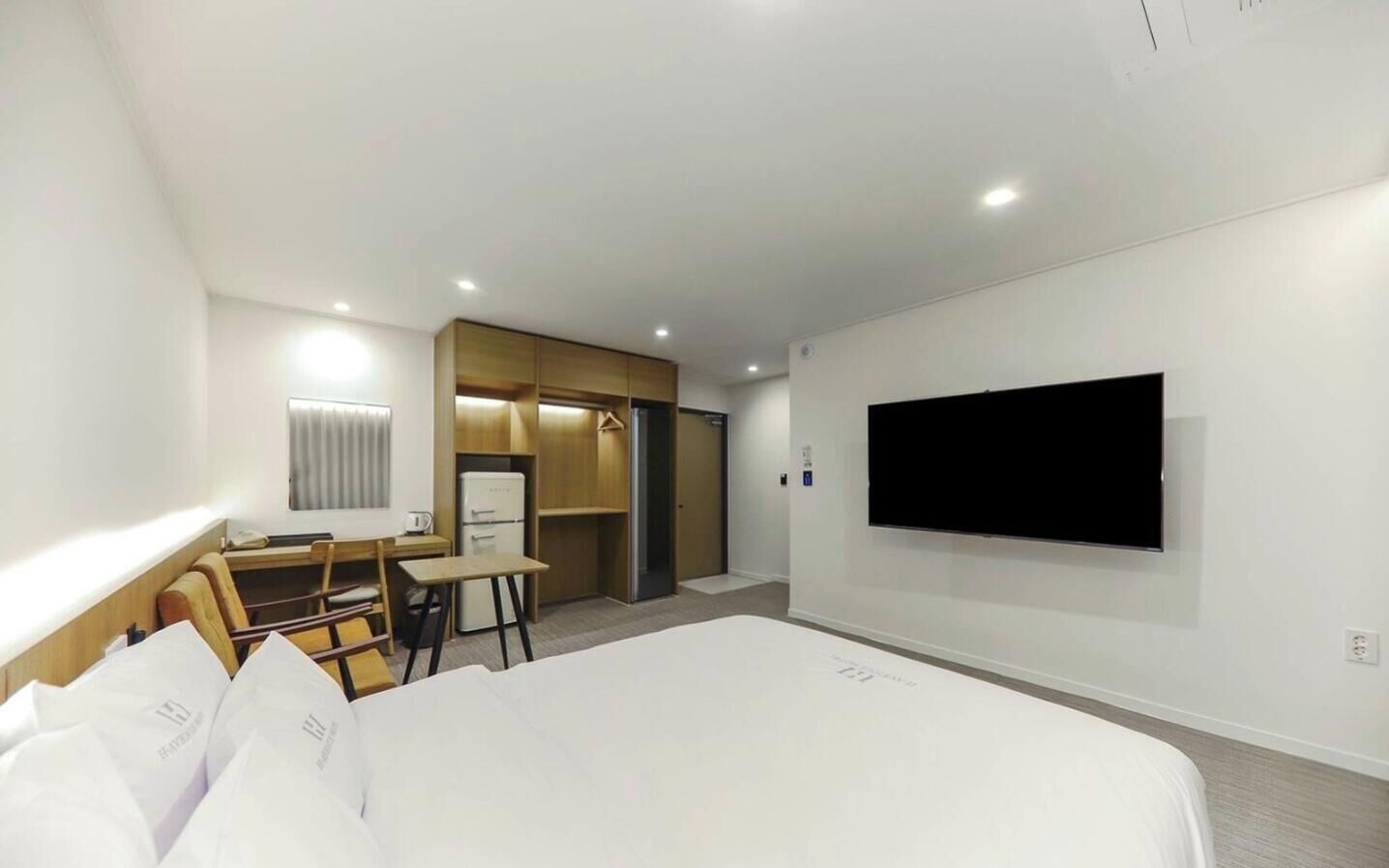 Habitación de hotel con cama, escritorio, silla, televisor y armario.