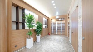 A modern hallway with wooden paneling, potted plants, and a patterned floor. - H Avenue Hotel Jeonju Terminal (Jeonju)