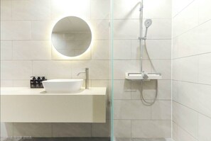 A modern bathroom with a round mirror, a white sink, and a shower with a handheld showerhead. - H Avenue Hotel Jeonju Terminal (Jeonju)