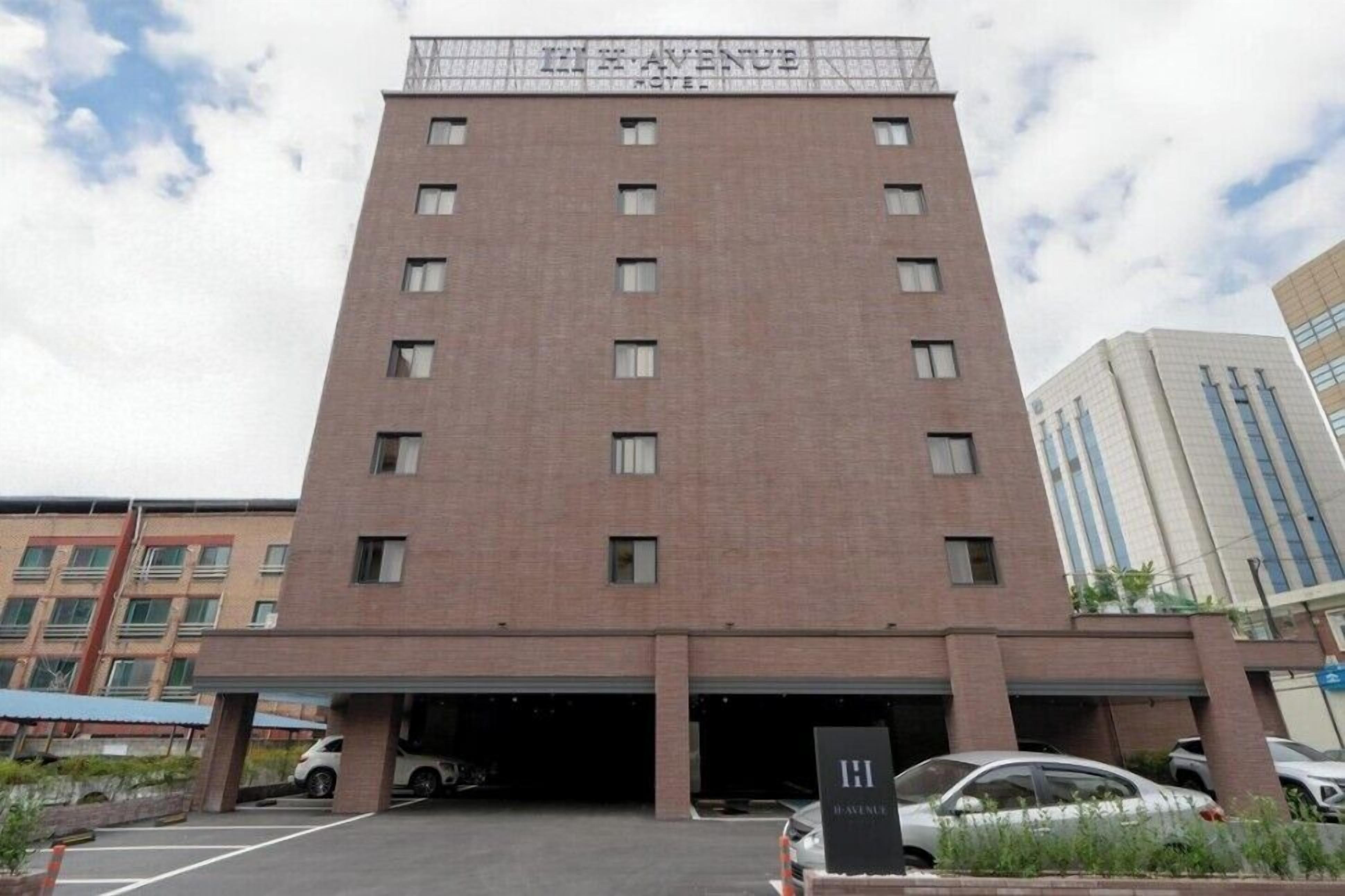 Um hotel de vários andares com fachada de tijolos e uma placa indicando "11 AVENUE HOTEL".